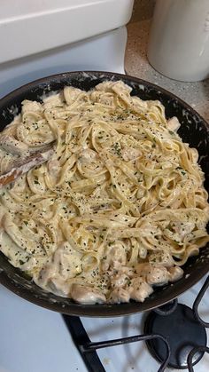 a pan filled with pasta and sauce on top of a stove