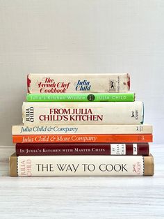 a stack of five books sitting on top of each other in front of a white wall