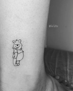 a black and white photo of a small bear tattoo on the right side of the leg