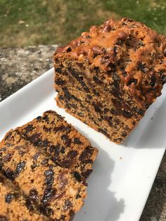 two slices of chocolate chip banana bread on a white plate with grass in the background