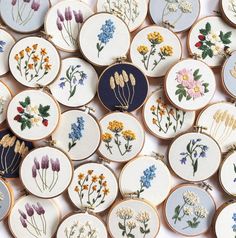 many embroidered flowers are displayed on wooden hoops