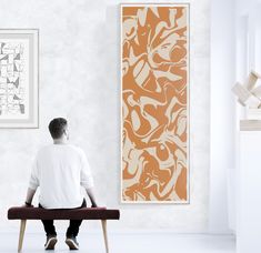 a man sitting on a bench in front of an orange and white wall art piece