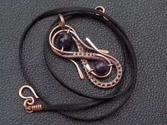 Wire wrapped pure copper and 8 mm purple Amethyst gemstones unisex infinity pendant necklace with 3 mm black leather cord and copper clasp . January - February birthstone perfect gift for Aquarius sign boyfriend or girlfriend , unique and special gift for husband and wife for 7th copper wedding anniversary . Pendant Lenght : 6 cm x 2 cm / 2.2" x 0.8 " (including the bail ) Copper is oxidized to give it an antique appearance.  Please read about copper care on Info & Faq section. Please be sure to Adjustable Purple Copper Wire Jewelry, Adjustable Purple Electroformed Jewelry, Adjustable Electroformed Purple Jewelry, Adjustable Black Copper Wire Jewelry, Copper Wedding Anniversary, Aquarius Sign, Copper Wedding, Infinity Pendant, February Birthstone