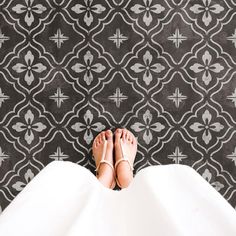 a woman's feet in white shoes standing on a black and white patterned floor