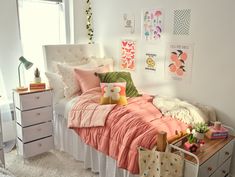 a bedroom with pink and green bedding, pillows and pictures on the wall above it