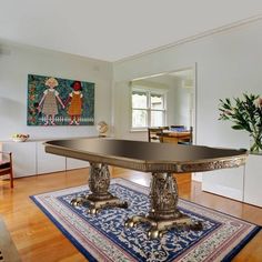 an elegant dining table in the middle of a room with hardwood floors and white walls