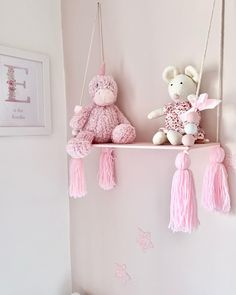 two stuffed animals sitting on top of a shelf in a child's room with pink decorations