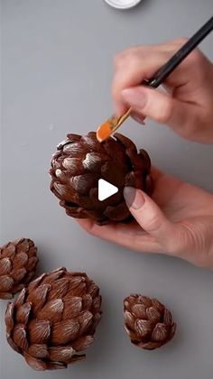 a person is painting some pine cones with acorns