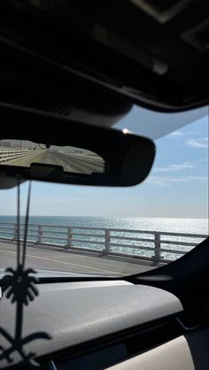 the view from inside a car looking out at the ocean and bridge that runs over it