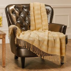 a chair with a blanket on top of it in front of a table and vase