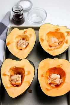 four pieces of buttered squash on a baking sheet with spoons next to them