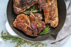 steaks in a skillet with herbs on the side