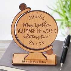 a wooden globe with writing on it and a pen sitting next to it, in front of a book