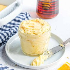 a glass jar filled with whipped cream sitting on top of a white plate next to an orange slice