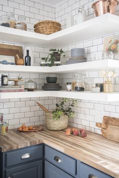 a kitchen with blue cabinets and white subway backsplash, wooden cutting board on the counter