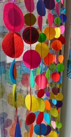 colorful paper circles hanging from the side of a window