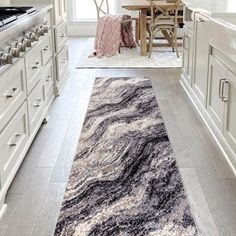 a kitchen with white cabinets and an area rug on the floor