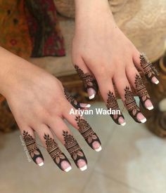 a woman's hands with henna tattoos on their fingers and hand, both decorated with