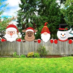 christmas yard decorations with santa claus, snowmen and reindeers on the side of a fence