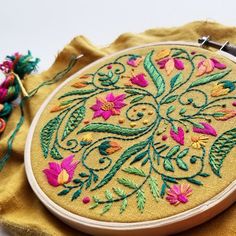 a close up of a embroidery on a piece of cloth next to a sewing needle