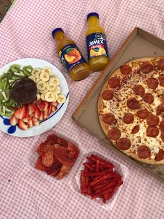 the pizza is ready to be eaten on the picnic table with fruit and veggies