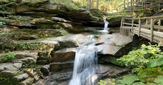 a wooden bridge over a small waterfall in the woods