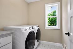 a washer and dryer in a small room with a window on the wall