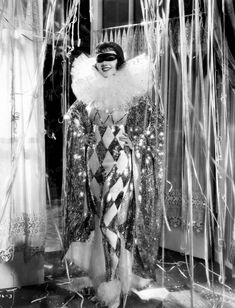 a woman dressed in costume standing next to curtains and drapes with lights on them