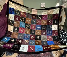 a woman is holding up a quilt made with various colors and designs on the fabric