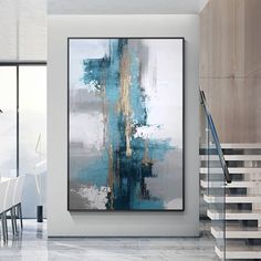 an abstract painting hangs on the wall next to a stair case and table with chairs