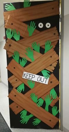 a classroom door decorated with green handprints and keep out stickers on it