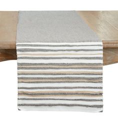 a striped table runner is on top of a wooden table with a white and gray stripe