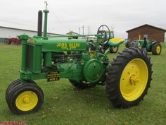 an old john deere tractor is parked in the grass with other tractors behind it