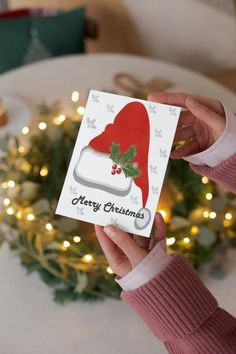 a person holding up a christmas card in front of a table