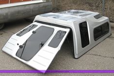 a white microwave oven sitting on the ground next to a metal object that looks like it has been broken