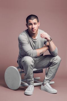 a man sitting in a chair with his legs crossed and hands on his knees, posing for the camera