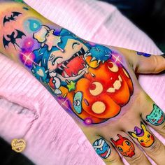 a person's hand with tattoos on it and an orange pumpkin in the middle