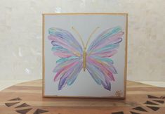 a painting of a colorful butterfly on a wooden table with white tiles in the background