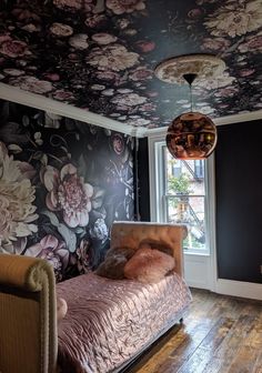 a bedroom with floral wallpaper and wooden floors