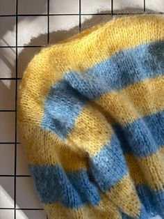 a yellow and blue blanket laying on top of a tiled floor