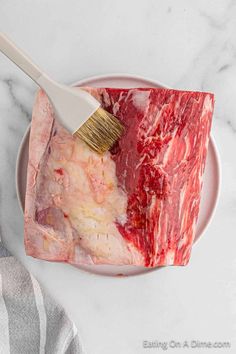 a piece of raw meat on a plate with a brush