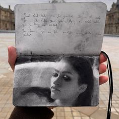 a person holding up a piece of paper with writing on it and a woman's face