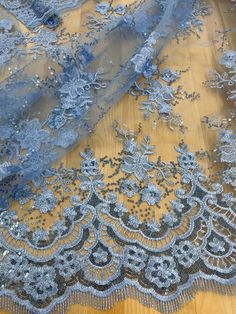 an image of a blue lace fabric on a wooden tablecloth with beads and sequins