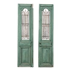 two green wooden doors with iron bars on the top and bottom, side by side