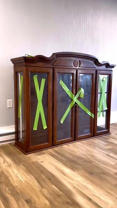 a wooden cabinet with green tape taped to the front and sides, sitting on top of a hard wood floor