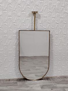 a mirror sitting on top of a wooden floor in front of a wall mounted shelf