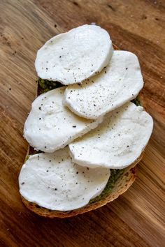 slices of bread topped with mozzarella and pesto on a wooden table top