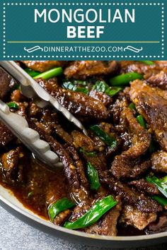 the beef dish is served in a bowl with tongs and green peppers on top