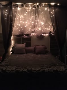 a bed covered in lights and pillows under a canopy