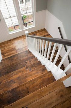 a wooden floor with white railings and windows in a home's entryway